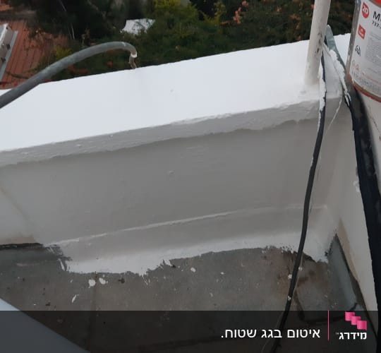 קיר אטום בצבע לבן עם דלי חומר איטום